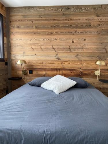 a bedroom with a bed with wooden walls and two lamps at Le Marlou in La Toussuire