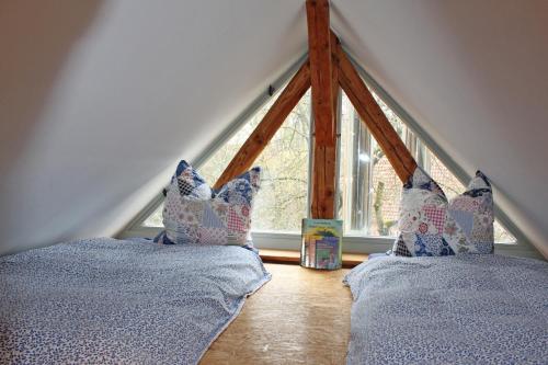 two beds in a attic with a window at Ferienwohnung auf der Rübenburg in Barnsen