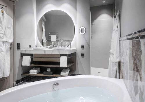a bathroom with a tub and two sinks and a mirror at Hotel Weisses Roessl in Kitzb&uuml;hel