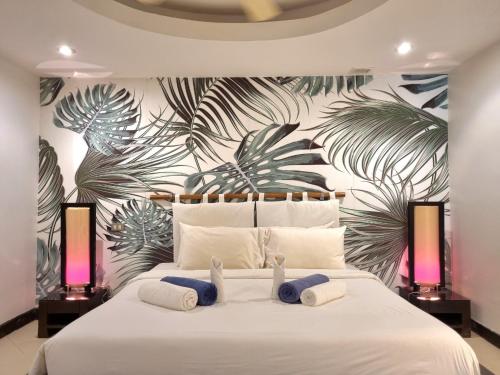 a bedroom with a large white bed with a tropical wallpaper at Kata Beach Aspasia Boutique Apartment in Kata Beach