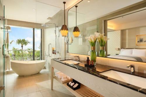 a bathroom with a tub and a bedroom at Padma Hotel Semarang in Semarang