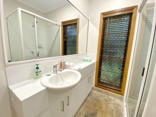 a white bathroom with a sink and a mirror at Mills Cottage in Arcadia