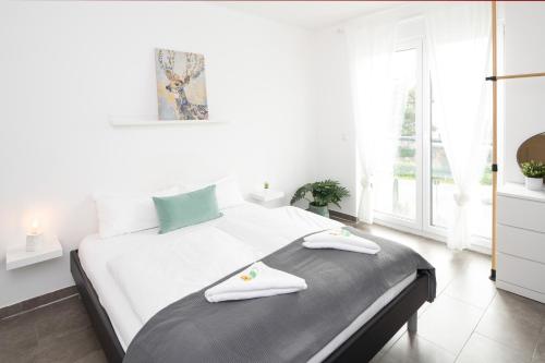 a white bedroom with a bed with two towels on it at Nibelungen Apartments in Worms