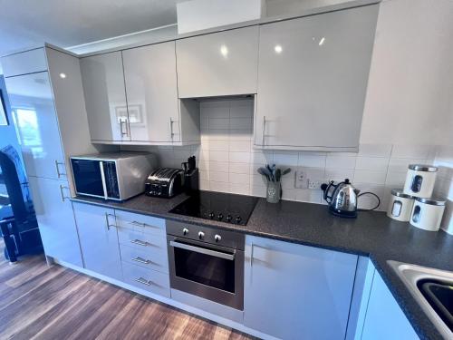 een keuken met witte kasten en een fornuis met oven bij Cydel Court in Kidlington