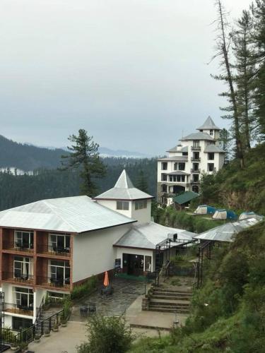 a group of buildings on top of a hill at Tethys Himalaya Narkanda in Nārkanda