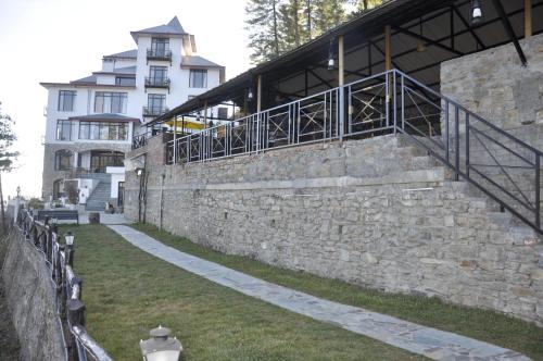a building with a stone wall and a fire hydrant at Tethys Himalaya Narkanda in Nārkanda