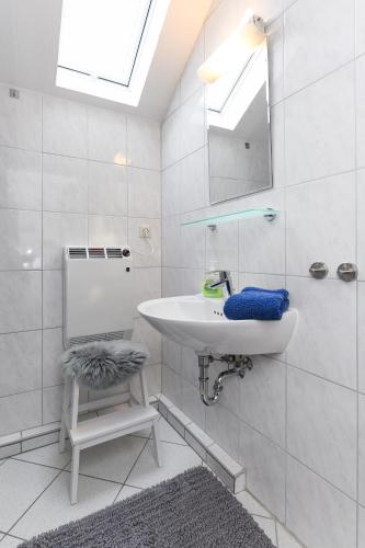 a white bathroom with a sink and a mirror at Ferienhaus Nordseekate in Stedesdorf