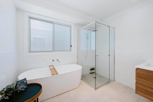 une salle de bain blanche avec une baignoire et une douche en verre dans l'établissement Helvetia - Modern Comfort meets Country Convenience, à Mudgee