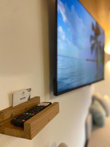a flat screen tv on a wall with a remote control at Best Butler: Studio Apartment *Balkon*Küche*Parken in Hopferau