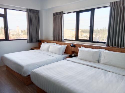 two beds in a hotel room with windows at Ocean Guest House in Magong