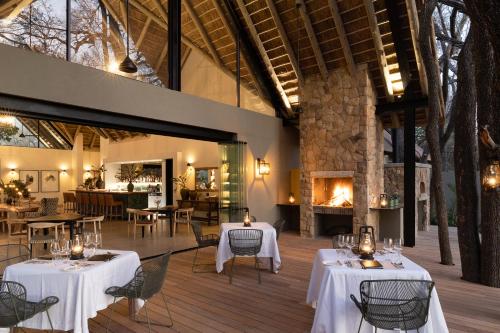 a restaurant with tables and chairs and a fireplace at Monwana in Thornybush Game Reserve