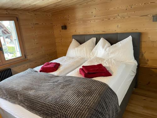Bett in einem Holzzimmer mit zwei roten Kissen darauf in der Unterkunft Chalet Swiss Alps in Grindelwald