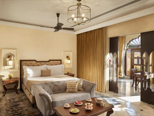 sypialnia z łóżkiem, kanapą i stołem w obiekcie Sawai Man Mahal w mieście Dżajpur