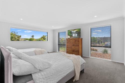 um quarto branco com uma cama e 2 janelas em Whai Awa Retreat - Mangawhai Holiday Home em Mangawhai