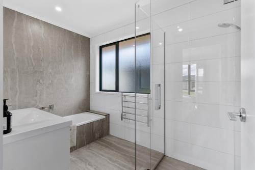 une salle de bain blanche avec une douche et un lavabo dans l'établissement Whai Awa Retreat - Mangawhai Holiday Home, à Mangawhai