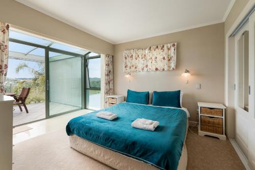 a bedroom with a blue bed and a balcony at Swallows Nest - Paihia Holiday Home in Paihia