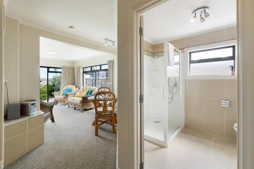 a bathroom with a shower and a living room at Swallows Nest - Paihia Holiday Home in Paihia