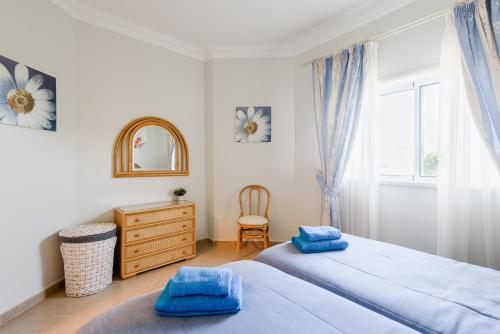 een slaapkamer met 2 bedden, een dressoir en een spiegel bij Boavista Golf Resort- Fairviews Villa in Lagos