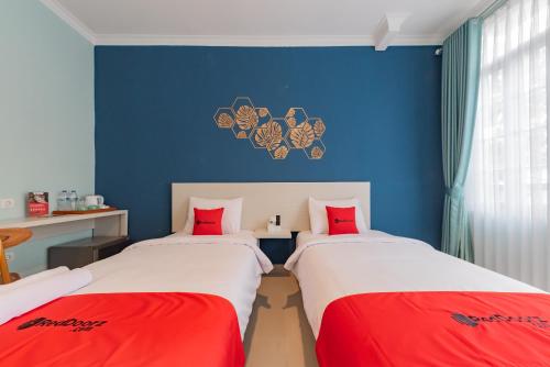 two beds in a room with blue walls and red pillows at RedDoorz Plus near Surapati Core in Bandung
