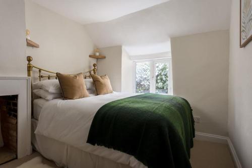 a bedroom with a bed with a green blanket on it at Charming 17th Century Cotswold Cottage in Adlestrop