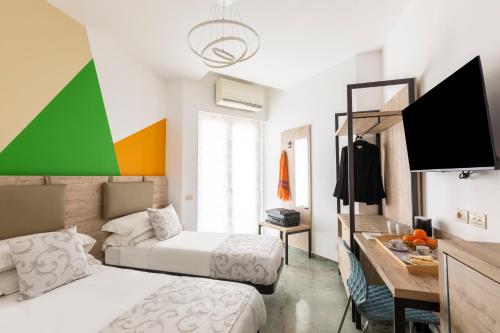 1 Schlafzimmer mit 2 Betten und einem Schreibtisch mit einem TV in der Unterkunft La Riviere Guesthouse Trastevere in Rom