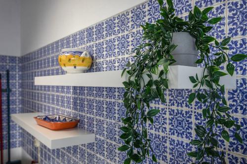 a bathroom with a blue tiled wall with a plant at Hopstays - Vilamoura Aldeia do Mar in Quarteira