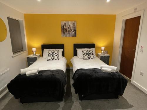 2 camas en una habitación con paredes amarillas en NelsonStays Self-Contained Studios Stoke on Trent, en Stoke on Trent