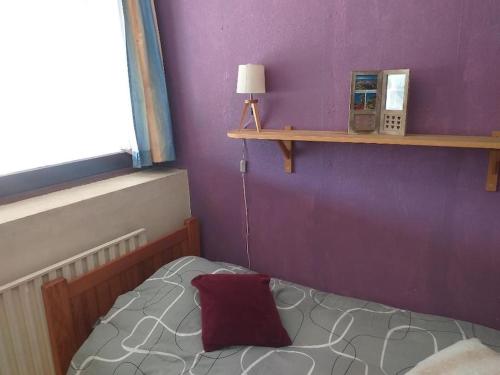 - une chambre avec des murs violets et un lit avec un oreiller rouge dans l'établissement Cap Dauphiné, à Grenoble