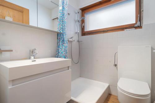 Appartement chaleureux à Ovronnaz في أوفروناز: حمام أبيض مع حوض ومرحاض