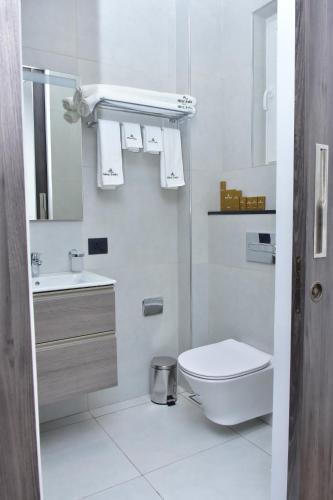 a white bathroom with a toilet and a sink at Hotel Stella in Kinshasa
