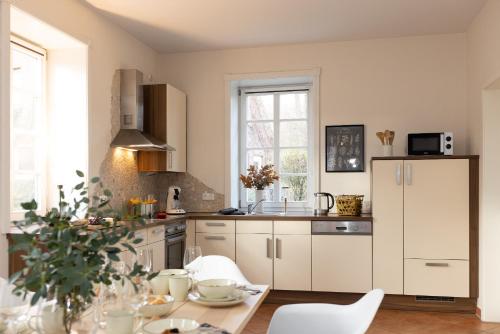 a kitchen with white cabinets and a table with chairs at ErholungNOW in Bispingen