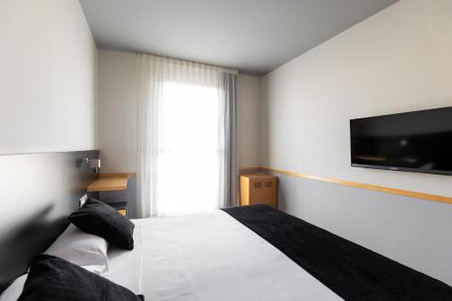 a bedroom with a white bed and a flat screen tv at Onix Liceo in Barcelona