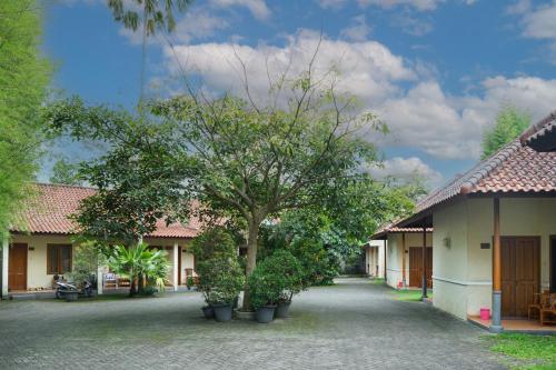 a building with a tree in the middle of a courtyard at Front One Resort Indraloka Temanggung in Temanggung