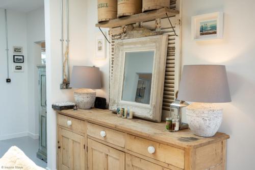 a dresser with a mirror and a lamp on it at Sea Breezes in Pagham