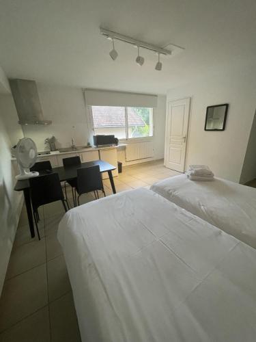 a white bedroom with a table and a kitchen at Grand lac in Duingt