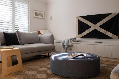 a living room with a couch and a ottoman at Sea Notes Yamba in Yamba