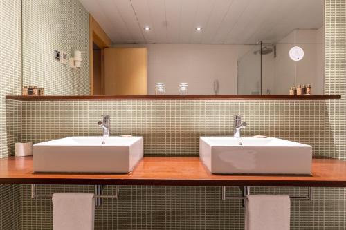 a bathroom with two white sinks and a mirror at Onix Liceo in Barcelona