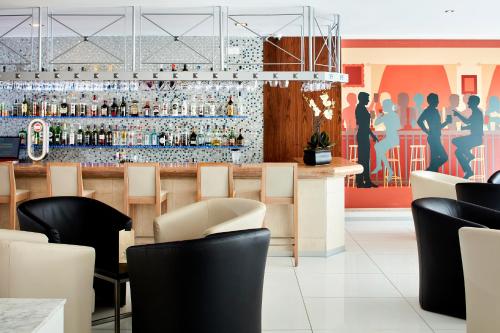 a restaurant with a bar with black chairs and a mural at Santa Eulalia Hotel & Spa in Albufeira