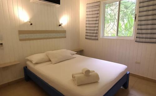 ein weißes Bett mit einem Handtuch auf dem Zimmer in der Unterkunft Boho lodge Montezuma l&l in Montezuma