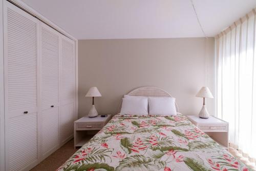 ein Schlafzimmer mit einem Bett mit zwei Nachttischen und zwei Lampen in der Unterkunft Lilikoi Condo in Kahuku