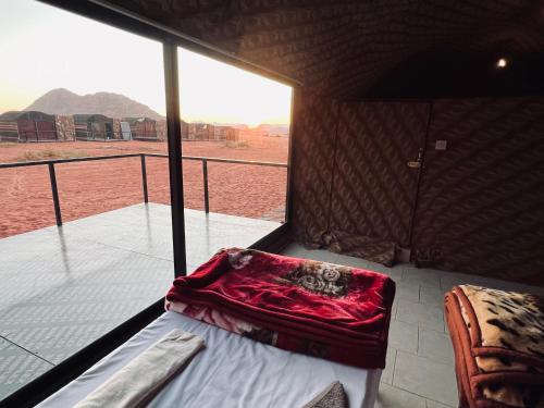 a room with a bed and a balcony with a view at Bedouin Lifestyle Camp in Wadi Rum