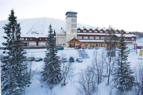 a large building in the snow with trees and cars at Lapland Hotels Äkäshotelli in Äkäslompolo