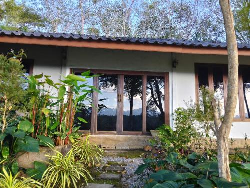 a house with a glass door in a garden at ภูริรักษ์ โฮมสเตย์ in Ban Pha Saeng Lang