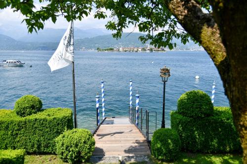 a dock with a flag and a boat in the water at Hotel Villa e Palazzo Aminta in Stresa