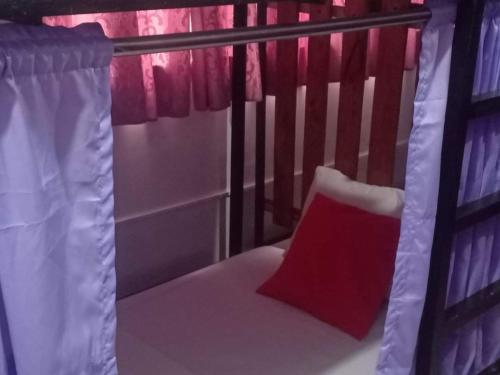 a bed with a red pillow and a curtain at Lojed Sean bed and space in Manila