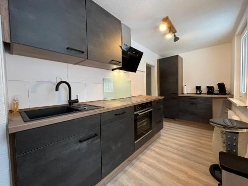 a kitchen with black cabinets and a sink at Breeman im Harz in Sankt Andreasberg