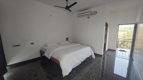 a white bedroom with a bed and a ceiling fan at HosteLife Gokarna in Gokarna