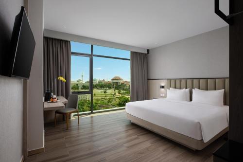 a bedroom with a white bed and a large window at Hotel Santika Batam in Batam Center