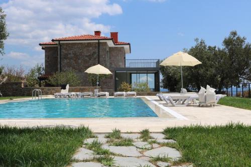 una piscina con sedie e ombrelloni di fronte a una casa di Assos Luna Houses a Ayvacık