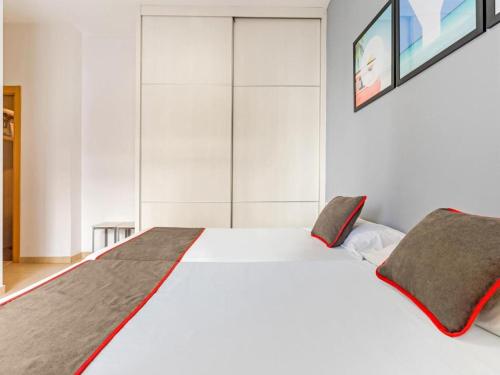 a bedroom with a large white bed with red accents at Luxury Apartments Puerto Valencia in Valencia